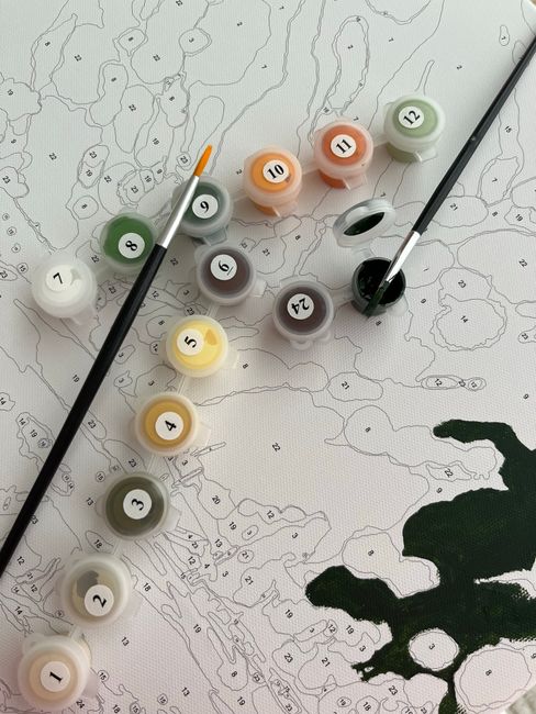 A detailed top-down view of a floral mapping activity, featuring rows of labelled paint pots in various shades including white, yellow, brown, green, grey, and orange, arranged on a white paper with a